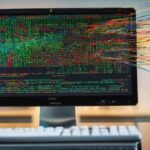 Computer monitor leaks strings of code out into the air.