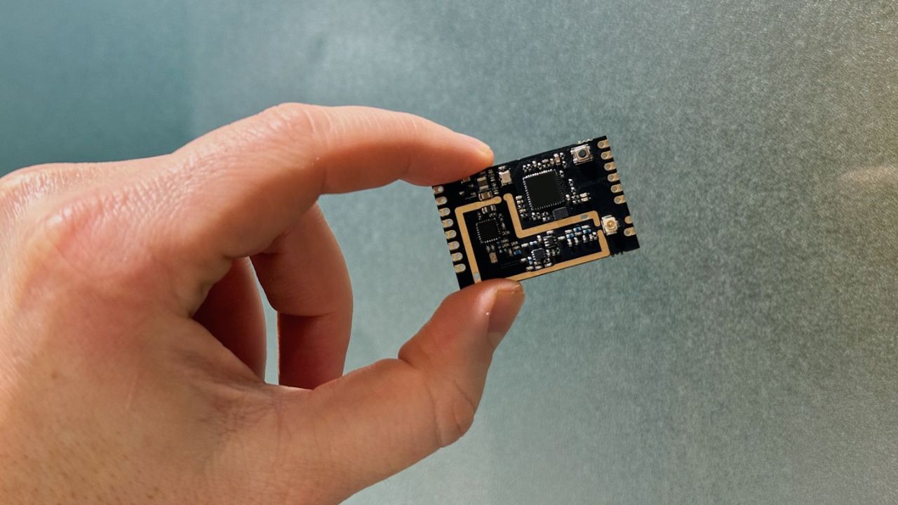 A hand holding the sine.link module for drones